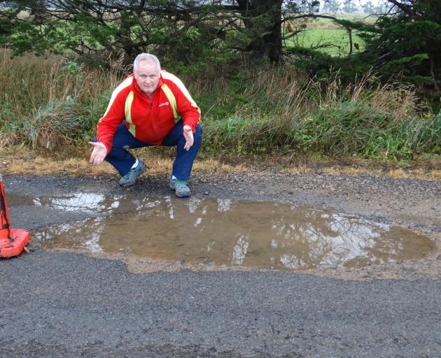 Dean Matheson examines a pothole on Otokia Rd West, Momona. JOSHUA RIDDIFORD