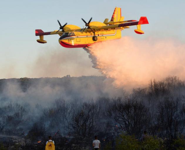 A firefighting plane drops water to extinguish a forest fire near Zadar, Croatia. Photo: Reuters