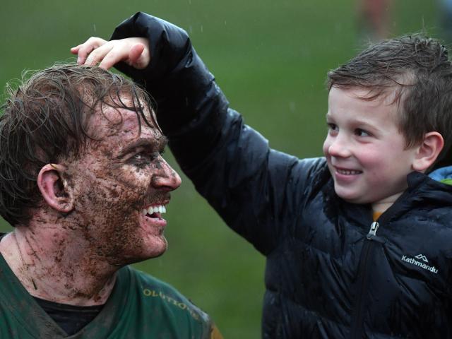 Ollie McLennan, 6, gives mud-splattered Green Island forward Amos Roddick a pat on the head after...