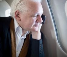 Julian Assange on the phone with wife Stella aboard a private jet to Canberra on Wednesday. Photo...