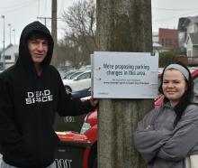 Harbour Tce residents Finlay Tomkins and Dana Wister next to a sign stating the proposed changes...
