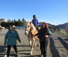 Alex is all concentration as he prepares to ride Cricket down the hill, with volunteers Alan...