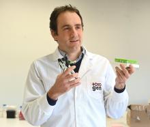 TotoGen co-founder Tim Hore displays an ear punch designed to easily collect DNA samples from...
