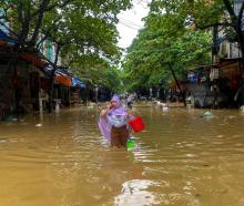 A woman wades through a flooded street following the impact of Typhoon Yagi, in Thai Nguyen City,...