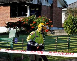 A firefighter outside the Auckland home where four children died. Another three people are in a...