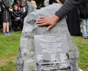 A hand touches a memorial stone during a ceremony at the Southern Cemetery in Dunedin yesterday....