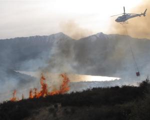 A helicopter attacks an out-of-control burn-off, covering an estimated 40ha, near the Remarkables...