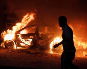 A man looks at a car on fire at the site of a bomb attack in Baghdad. REUTERS/Ahmed Saad