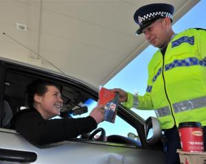 Constable Dave Bullot hands an ice scraper and free coffee to motorist Rachel Ovens at BP Connect...