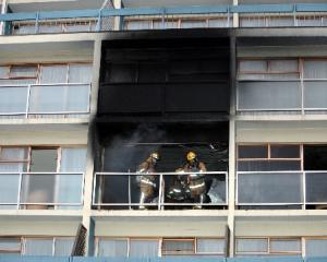 Firefighters with breathing apparatus check the room where a fire broke out on the third floor of...
