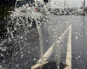 Heavy rain causes water to squirt out of a manhole in Barr St yesterday.