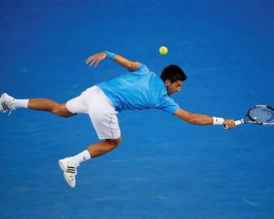 Novak Djokovic lunges to hit a return against Milos Raonic during their men's singles...