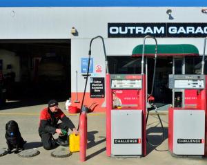 Outram Garage  owner-operator Ray Warnoch, who fills  a jerry can for a customer as his dog Tess...