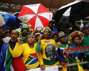 People sing and dance in heavy rain while waiting for the start of the official memorial service...