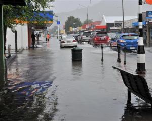 Traffic displaces water, making wake waves on flooded Gordon Rd on Saturday. Photos by Peter...