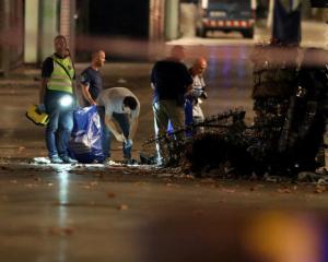 Forensic police officers search for clues near the area where a van crashed into pedestrians at...