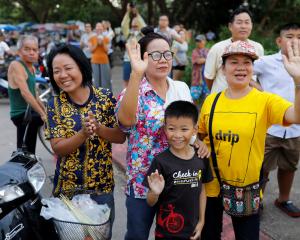 Onlookers wave as an ambulance carrying rescued schoolboys leaves a military airport in Chiang...