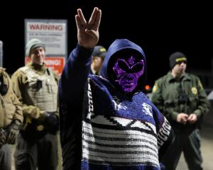 An attendee wears an alien mask at the gate of Area 51 as an influx of tourists responding to a...