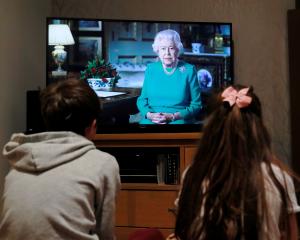 Noah (9) and Milly (7), of Hertford, watch Queen Elizabeth during a televised address to the...