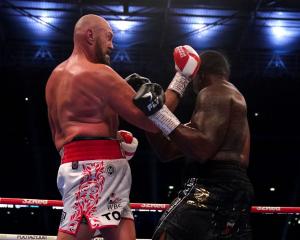 Tyson Fury (left) lands a punch to knock down Dillian Whyte during their clash at Wembley Stadium...