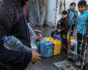 Palestinians carry containers of drinkable water collected from mobile barrels. UNRWA has been...