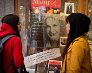 Customers look at a window display congratulating Canadian author Alice Munro at her own...