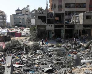 People walk among debris after an Israeli strike on Nuseirat refugee camp in the central Gaza...