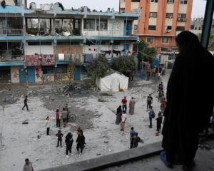 Palestinians inspect the site of an Israeli strike on a UNRWA school sheltering displaced people...