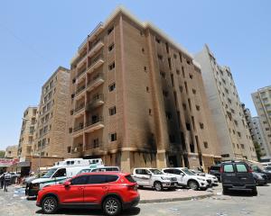 Emergency services outside a building damaged by a deadly fire, in Mangaf, southern Kuwait. Photo...