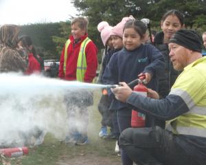 Leon Slee shows Glenavy School pupil Dominique Descallar, 7, how to operate a fire extinguishe....