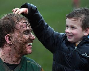 Ollie McLennan, 6, gives mud-splattered Green Island forward Amos Roddick a pat on the head after...