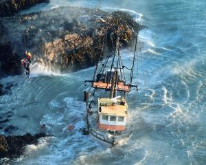 Rescue swimmer Ben Davidson and the skipper of the sinking Tamahine are winched to safety after...