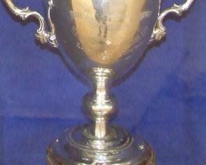The White Horse Cup, mounted in its protective glass and wood display case. The cup is contested...