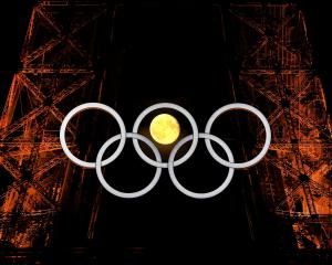 The moon makes an appearance through the Olympic rings on the Eiffel Tower in Paris. PHOTO: REUTERS