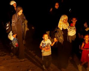 Palestinians who fled the eastern part of Khan Younis walk after they were ordered by the Israeli...