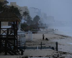 People stand on the beach in the tourist hotspot of Cancun in Mexico, awaiting the arrival of...