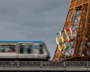 An elevated metro train passes over the Pont de Bir-Hakeim bridge, as the Eiffel Tower displays...