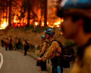 Firefighters stand by the road as the Park Fire burns, near Jonesville, California. Photo: Reuters