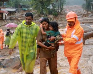 Rescuers help residents move to safety after landslides in the hills in Wayanad, in the southern...