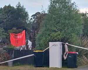 Investigators in boiler suits  comb over the scene of a fatal house fire in Manapouri. PHOTO:...