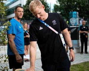 Finn Butcher touches the pounamu for luck at the Olympic Village in Paris. PHOTO: NZOC