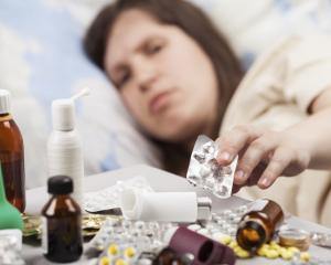 Woman sick in bed with pills, cold. Photo: Getty Images