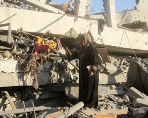 A Palestinian woman inspects the site of a former school, which was destroyed in an Israeli air...