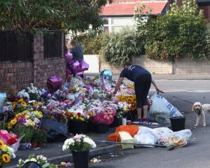 A woman arranges flowers at a makeshift memorial in&nbsp;Southport allowing people to pay their...