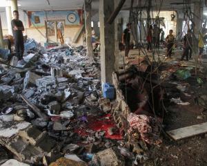 Palestinians survey damage at the site of an Israeli strike on a school sheltering displaced...