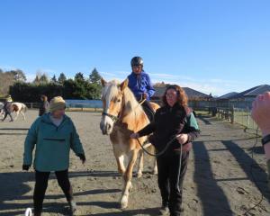 Alex is all concentration as he prepares to ride Cricket down the hill, with volunteers Alan...
