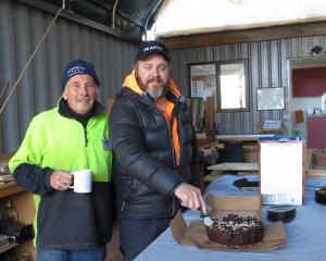 Shed manager Dennis Booth (left) and committee member Luke Win cut the cake at the celebrations...