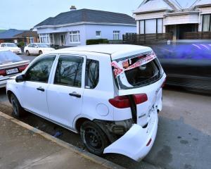 The rear bumper hangs from a car parked in Macandrew Rd, South Dunedin. A 15-year-old boy was...