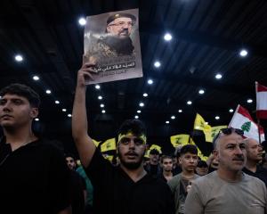 A supporter holds a poster of Hezbollah's top commander Fuad Shukr during a ceremony to mark the...