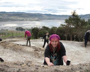 Dunedin city councillor Mandy Mayhem plants a kānuka tree on Sunday next to a cycle trail under...